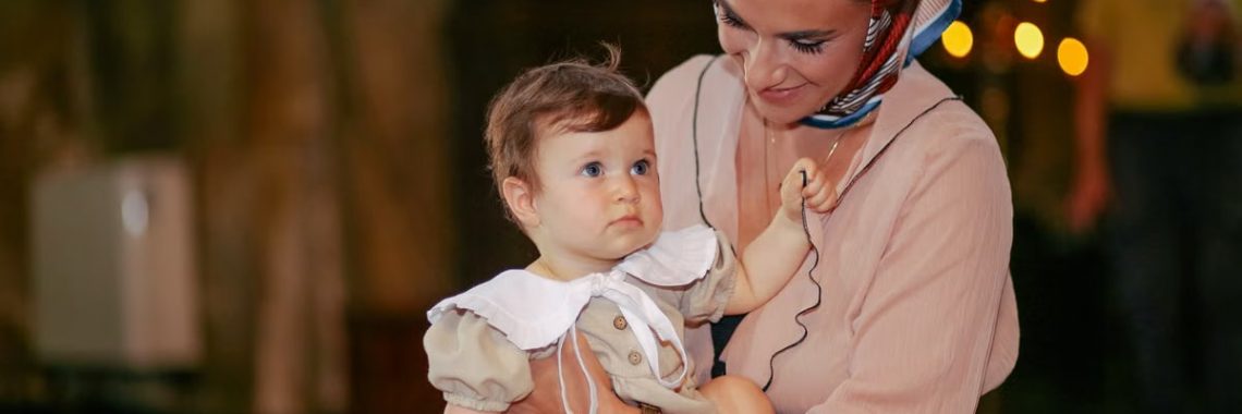 A mother lovingly holds her baby during a church ceremony.